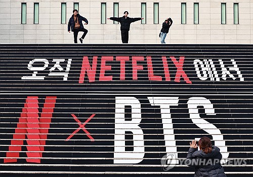 El 11 de marzo de 2026, unos turistas se toman fotos con una instalación callejera para promocionar el concierto de BTS en la plaza de Gwanghwamun, en el centro de Seúl.