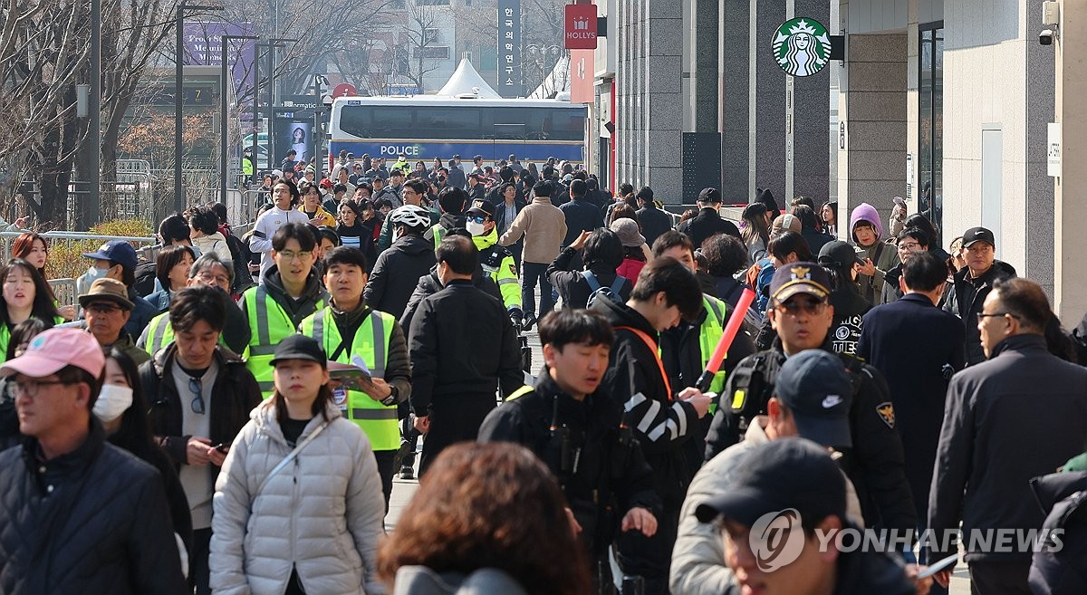 Las personas y agentes de policía llenan un espacio cerca del recinto donde se celebrará el concierto de regreso de BTS, el 21 de marzo de 2026, en la plaza de Gwanghwamun, en el centro de Seúl.